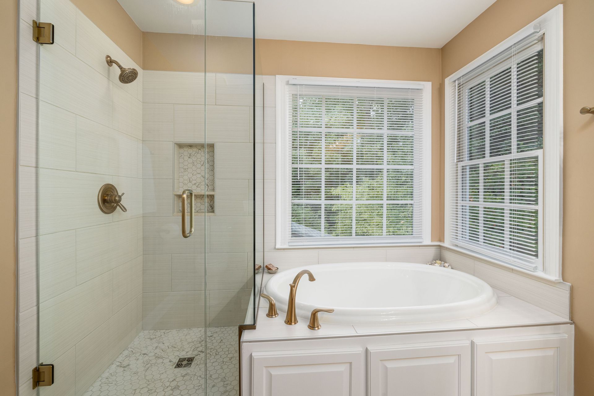 Elegant modern bathroom featuring a bathtub with gold fixtures and a glass-enclosed shower with tiles.