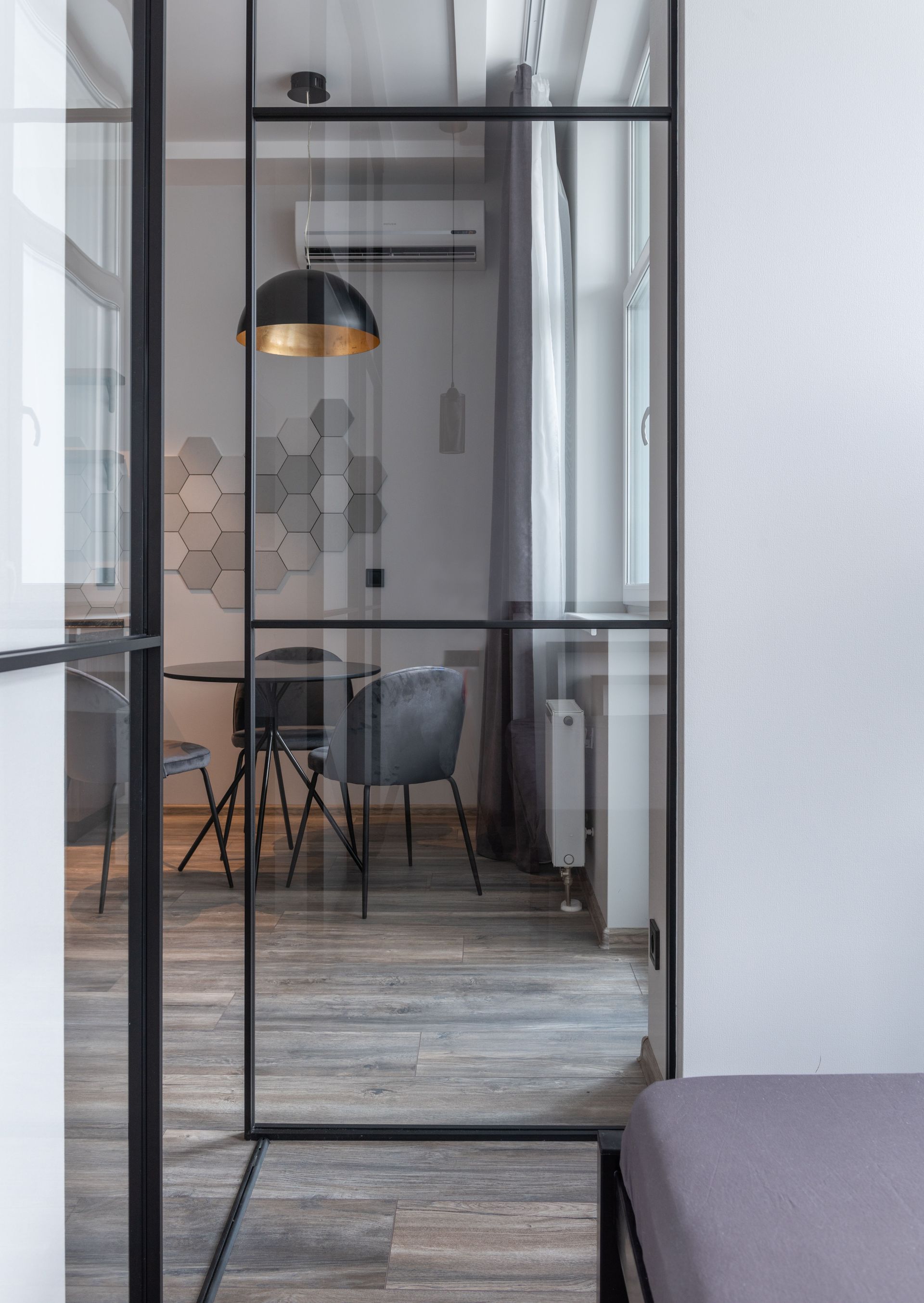 Modern living room interior with lamp and glass partition against table with chairs in house