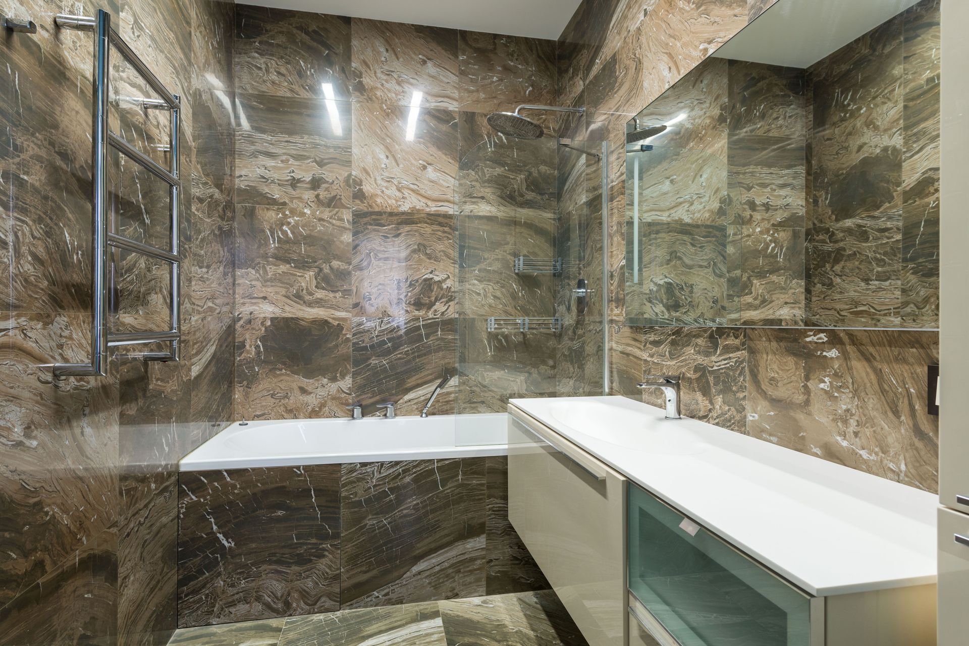 Bath placed near sink on cabinet at wall with mirror in modern light bathroom with heated towel rail at home